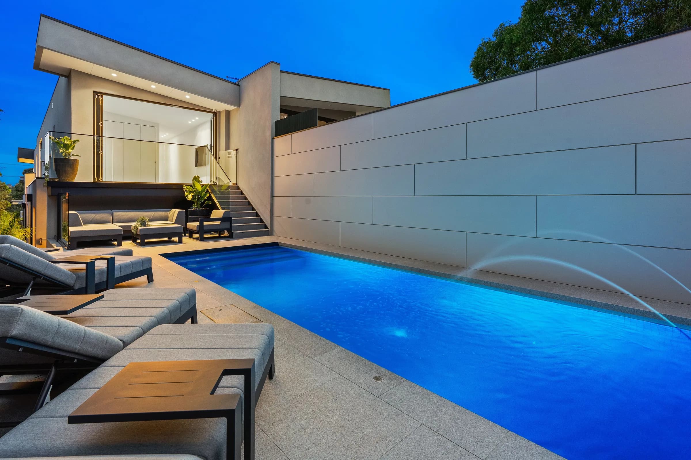 Evening view across the sunken pool courtyard to the rebuilt two-storey home
