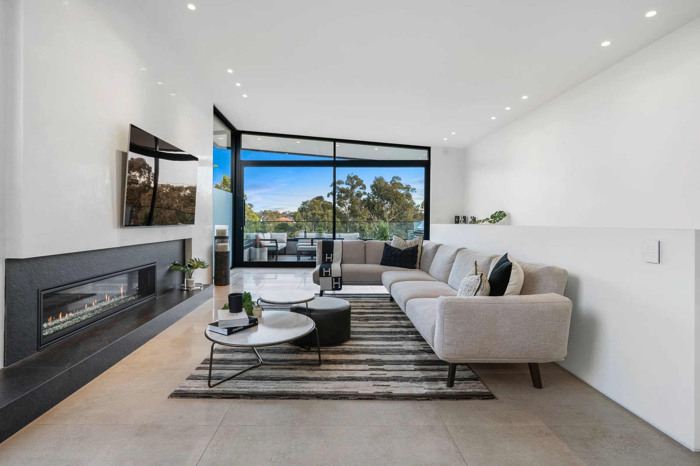 Living room with gas fireplace and treetop outlook through corner glazing