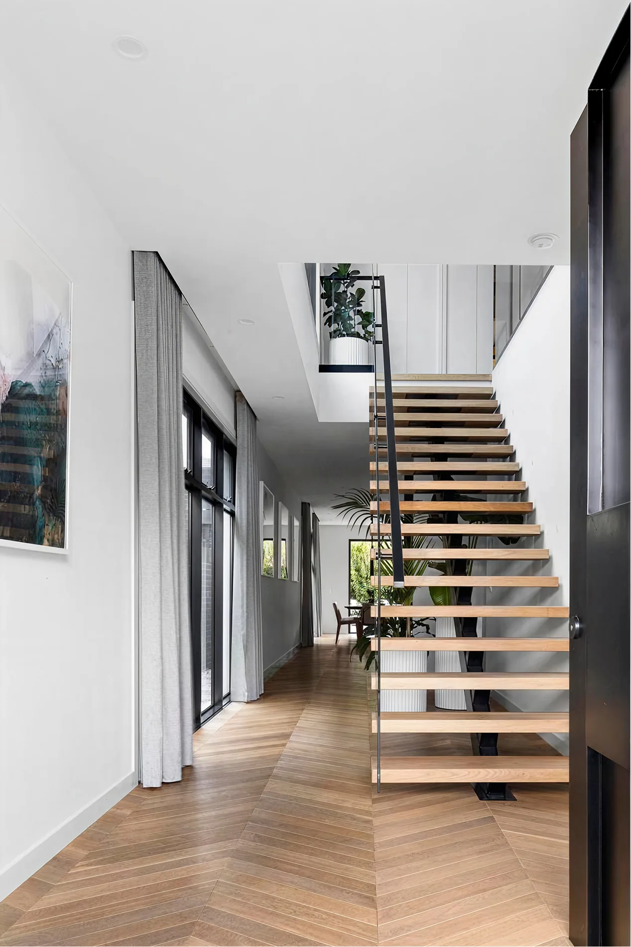 White hallway with floating timber stair and herringbone floor