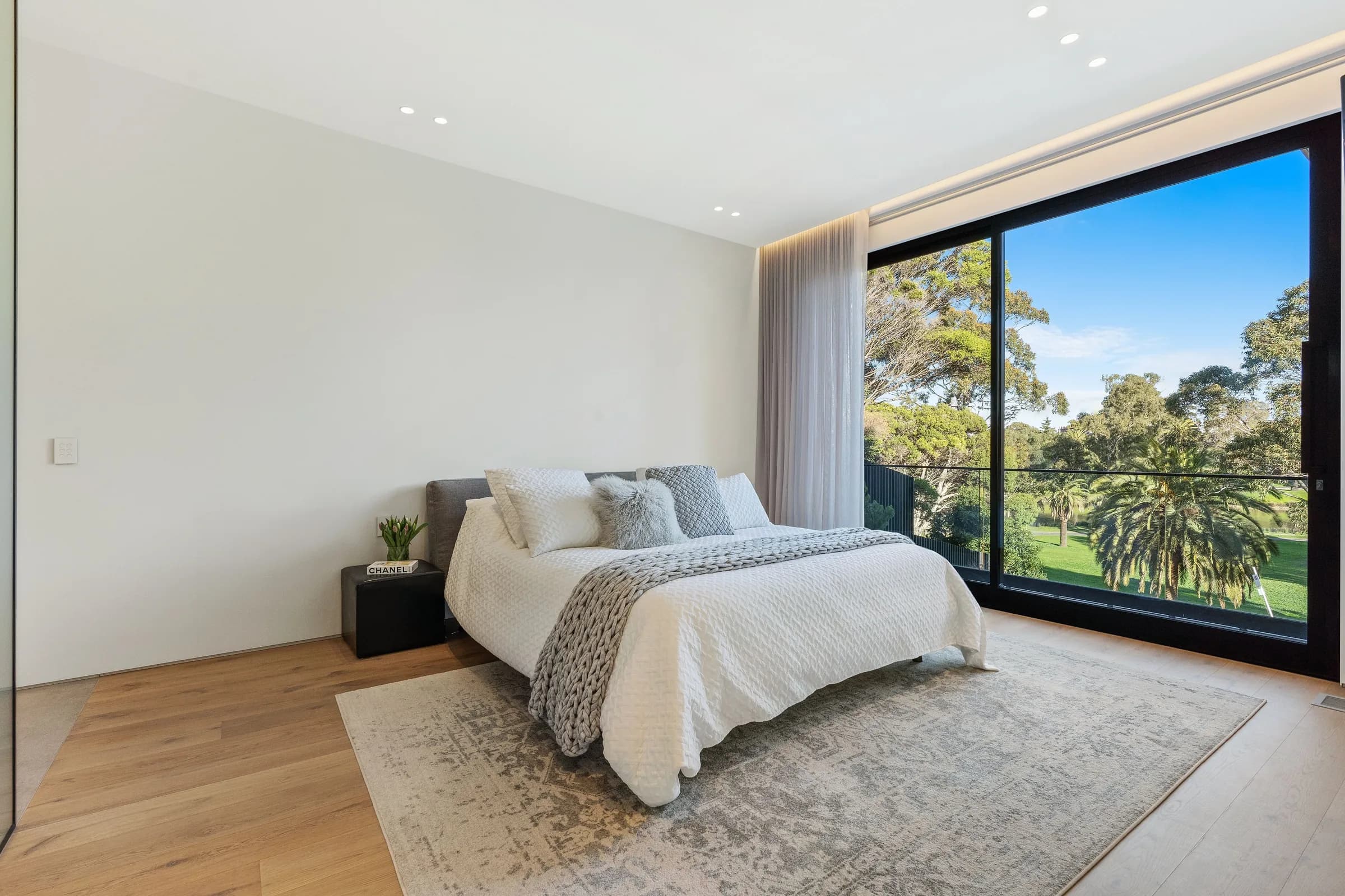 Master bedroom with full-width window framing parkland trees