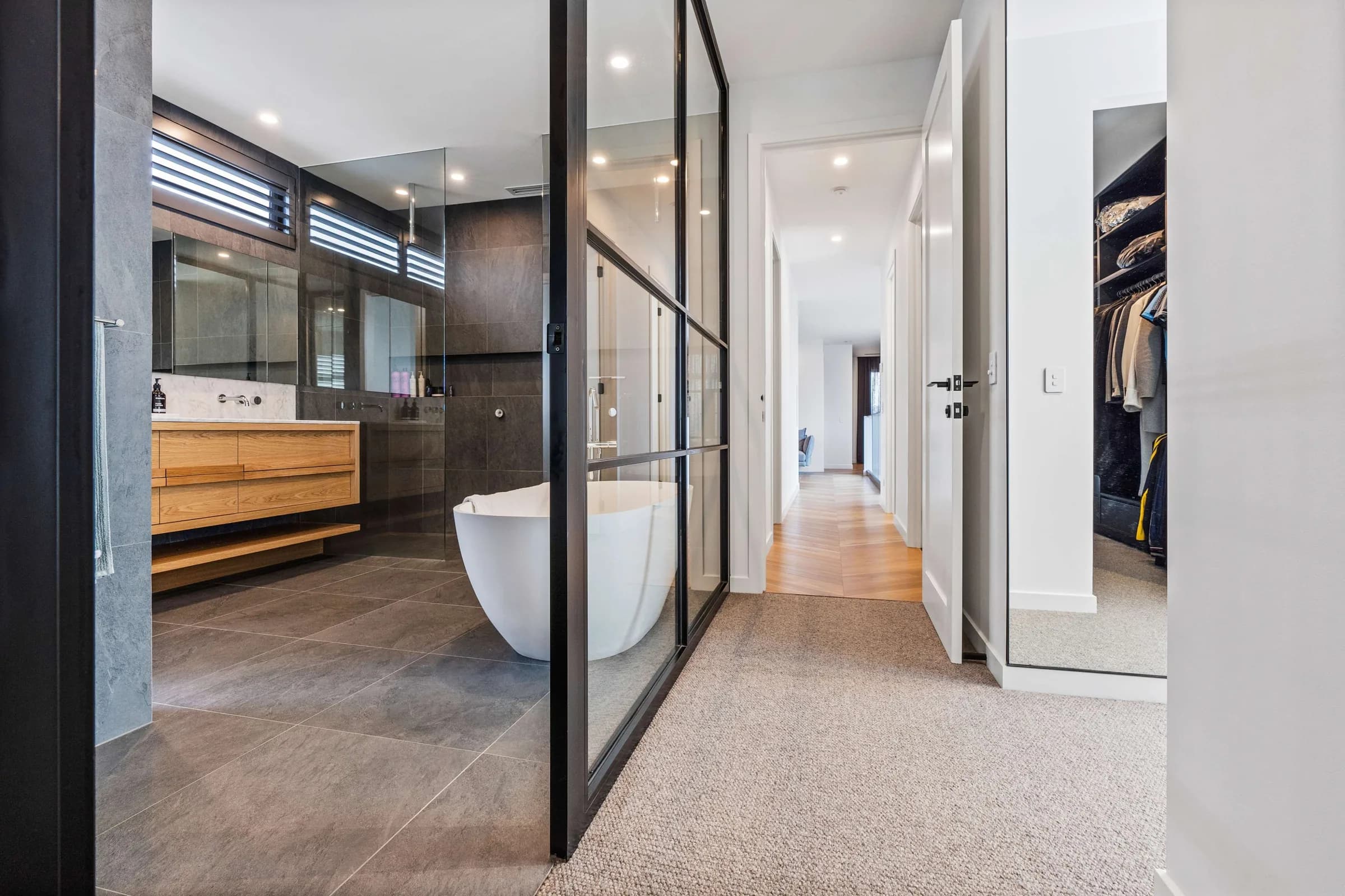 Black-framed glass partition around a freestanding tub